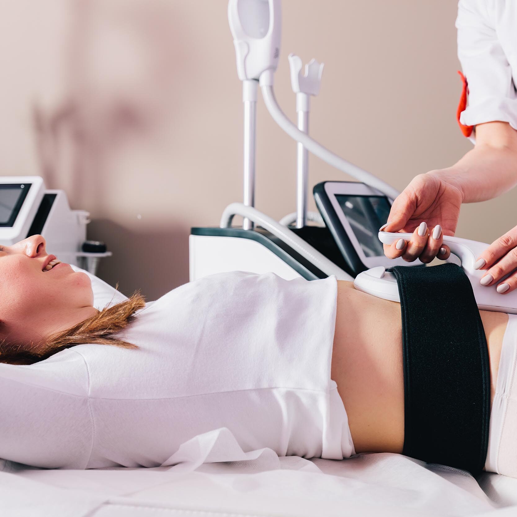 Woman getting ems treatment on abdomen to burn fat and build muscles, slimming technology